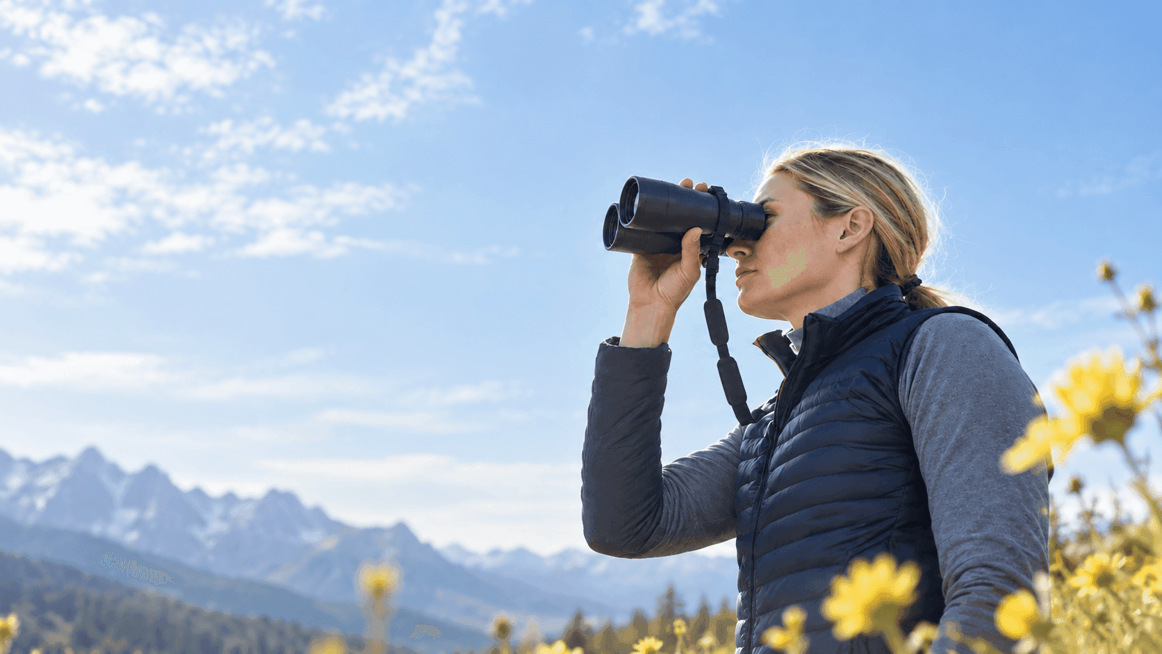 Woman looking through binoculars in a mountain landscape